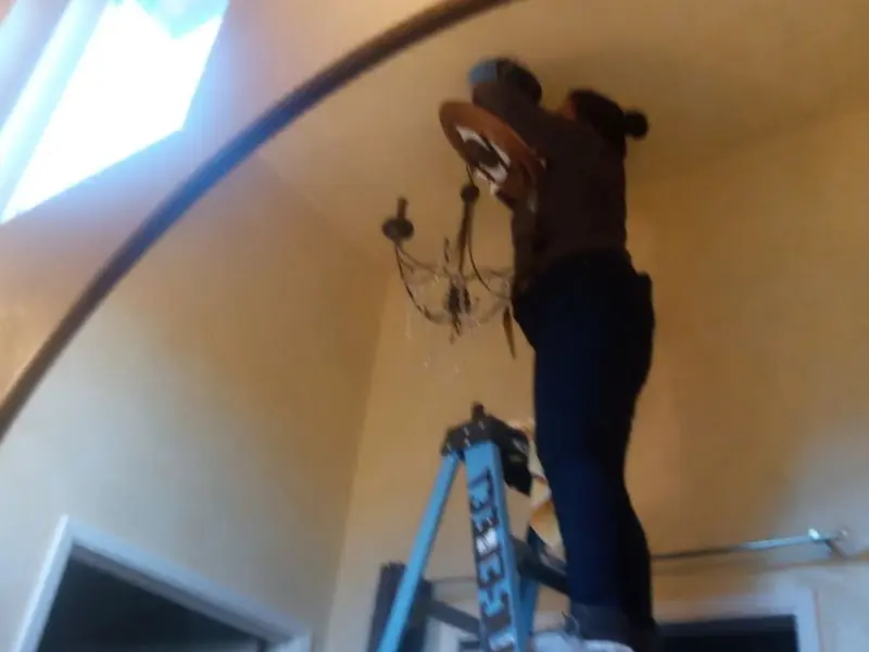 Electrician installing a chandelier in a Beverly Hills residence